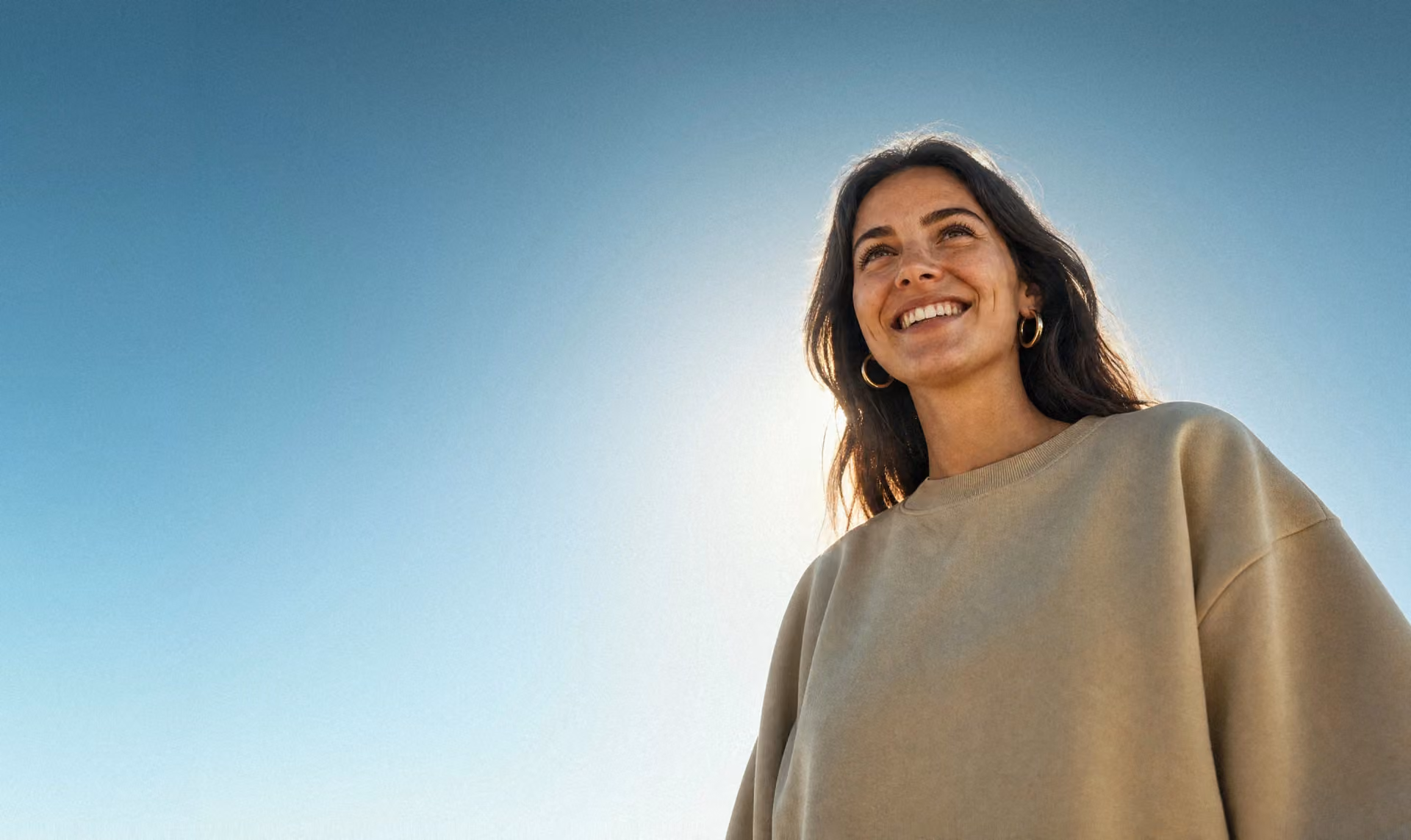 A smiling student under a clear blue sky